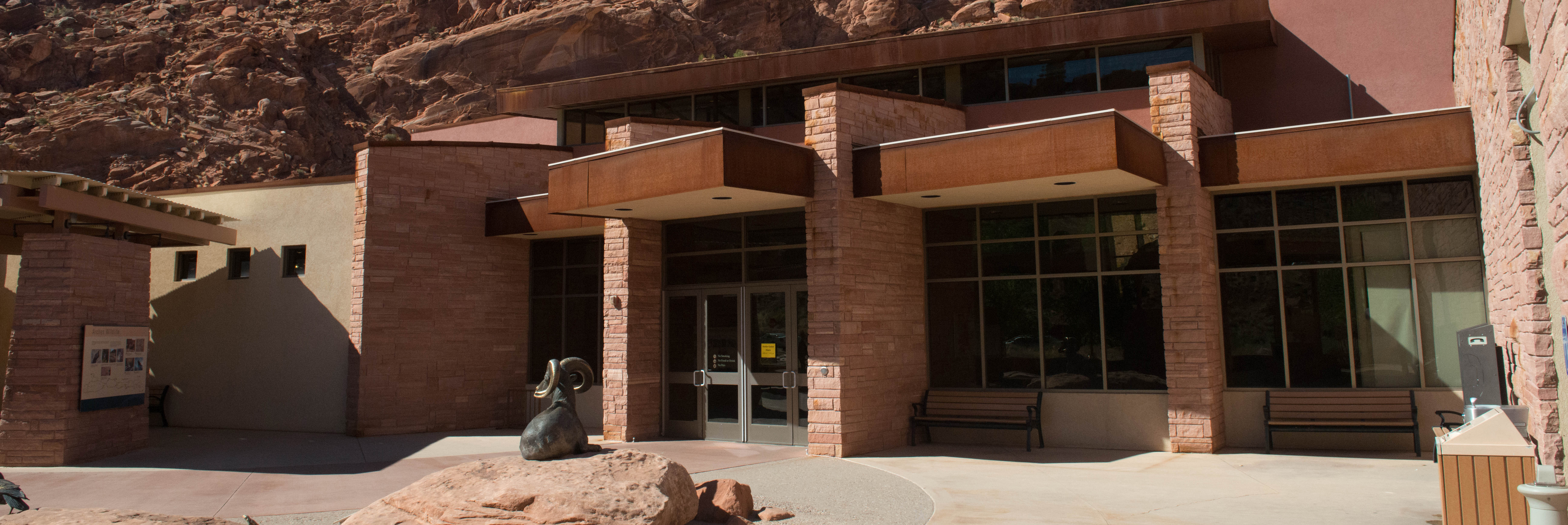 a tan building with red cliffs in the background