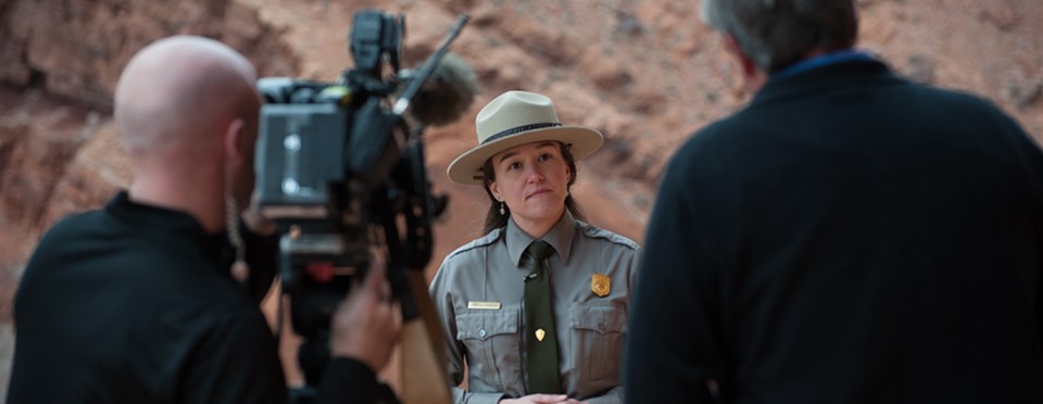 a park ranger stands in front of a video camera a park ranger stands in front of a video camera