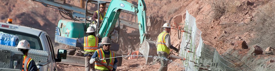 construction workers and a green backhoe at a construction site construction workers and a green backhoe at a construction site