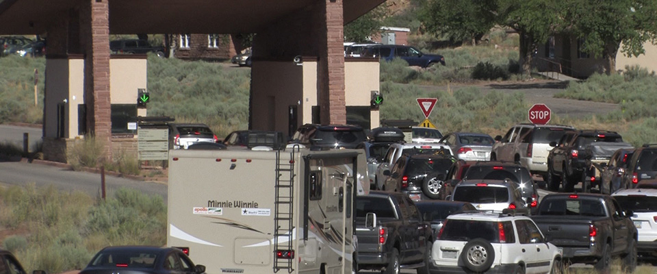 many vehicles line up at an entrance gate many vehicles line up at an entrance gate