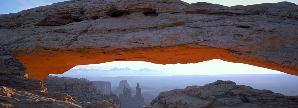 A wide, stone arch with mountains in the distance A wide, stone arch with mountains in the distance