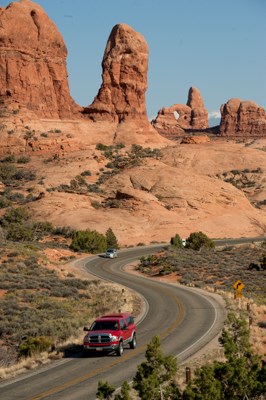 a red truck drives a road with a stone arch in the background a red truck drives a road with a stone arch in the background