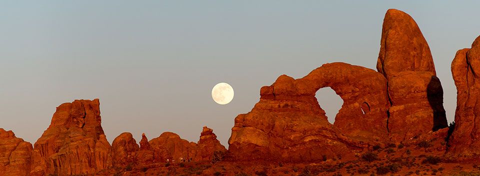 a large, stone arch with the full moon rising above it a large, stone arch with the full moon rising above it