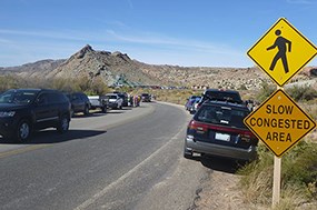 A road sign reading "Slow Congested Area" with parked cars.