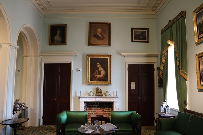 Parlor with green furniture and paintings on the wall