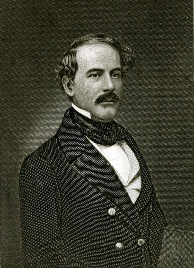 A young man with a suit and black mustache