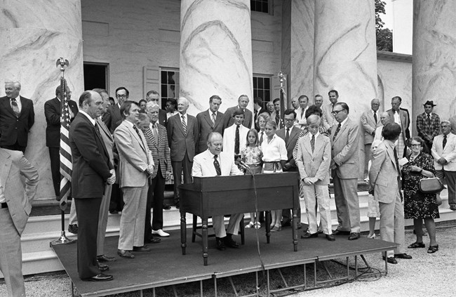 Ford signing a document on the portico of Arlington.