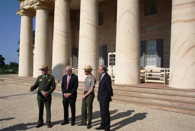 NPS Director Jon Jarvis, David Rubenstein, Brandon Bies, and National Park Foundation President and CEO Neil Mulholland stand before a row of columns at Arlington House.