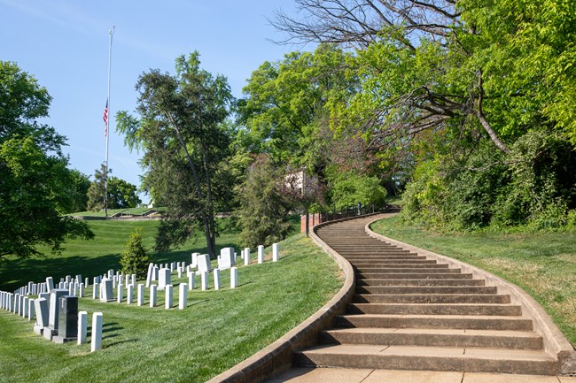 A curving set of steps lead up a grassy hill with headstones.