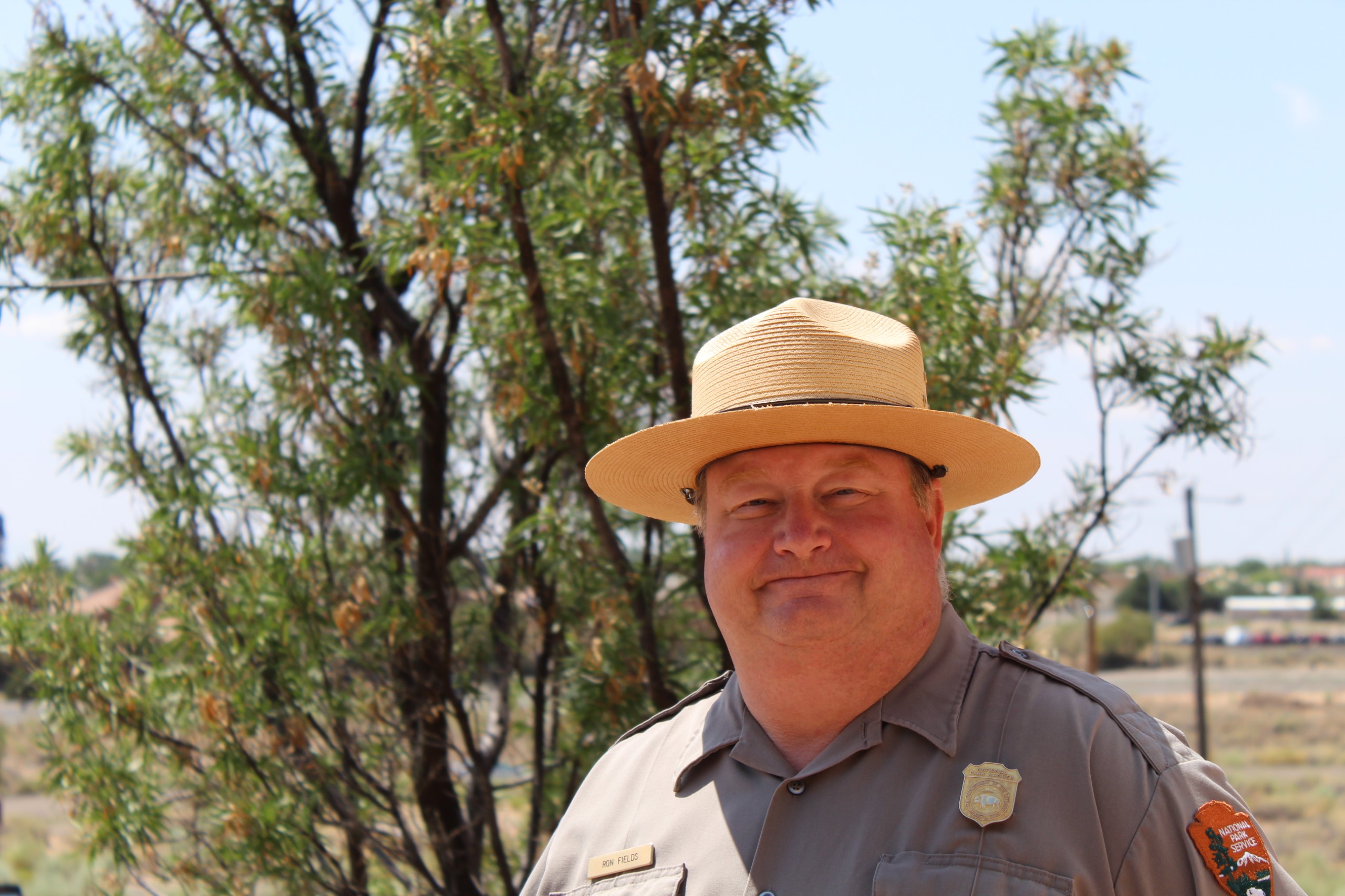 Ron Fields Man in uniform and a hat stand standing in front of a tree.
