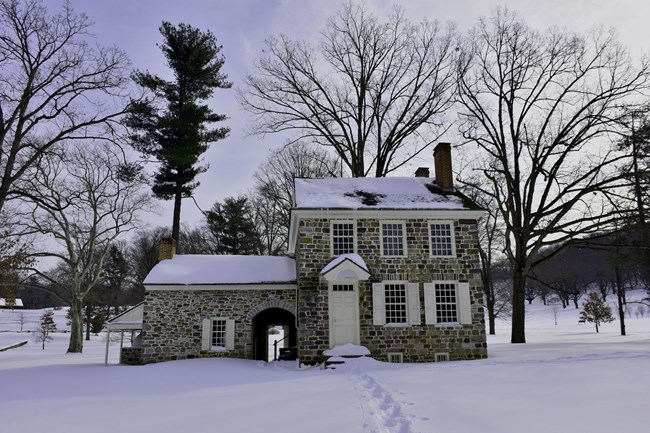 A three story stone building in a snowy field.