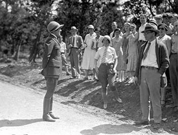 Visitors at Grand Canyon in 1931 listen to a female uniformed ranger give a talk.
