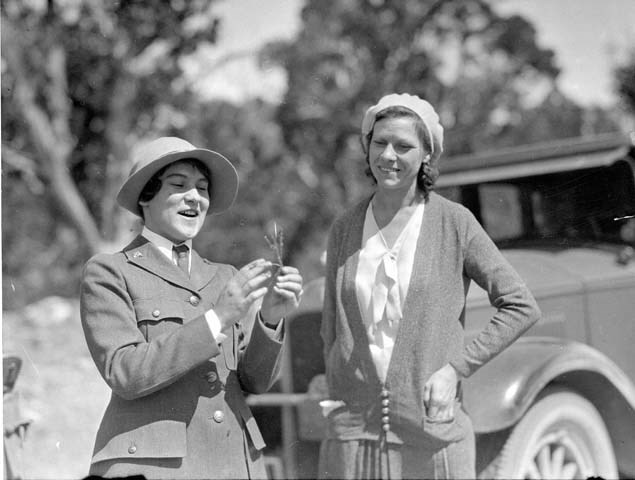 Polly Mead in NPS uniform shows a plant to a woman during a tour.