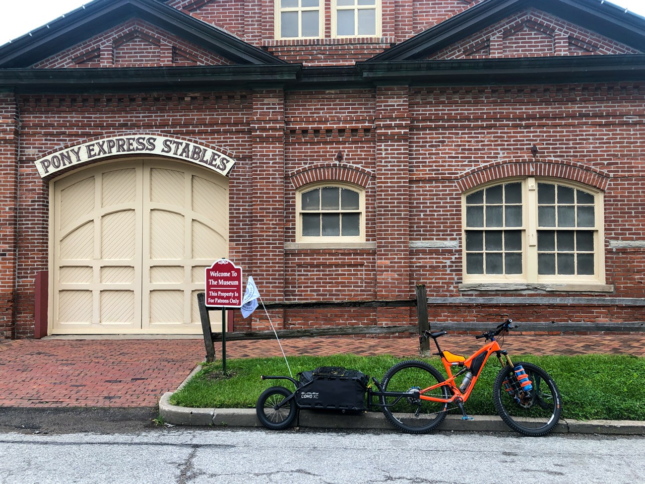 An orange bicycle in front of a historic brick stables.