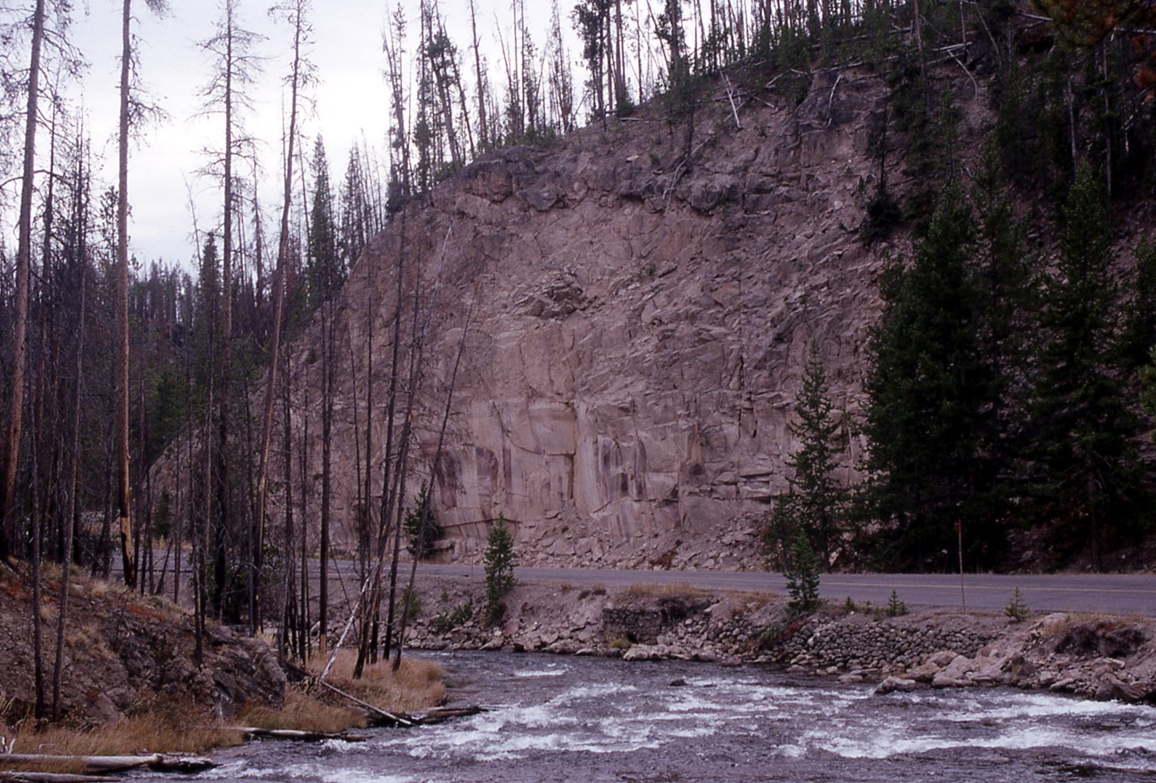 photo of a river, a road, and a rocky cliff road-cut