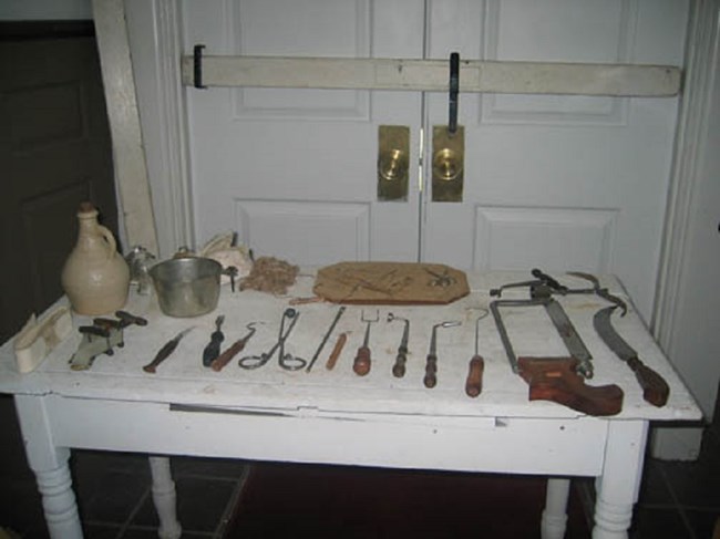 White table with metal tools and wooden tools, and a door behind the table