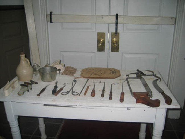 015_hospitaltable White table with metal tools and wooden tools, and a door behind the table