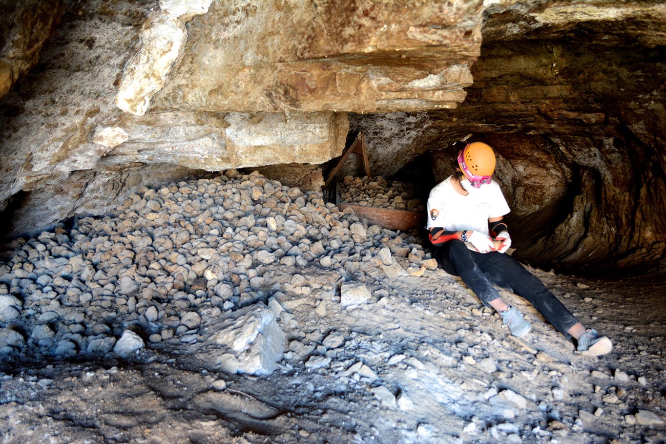 A person sitting in a cave examining fossils