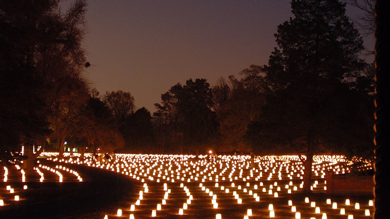 Poplar Grove Luminary Thousands of luminaries light of the headstones of a cemetery.