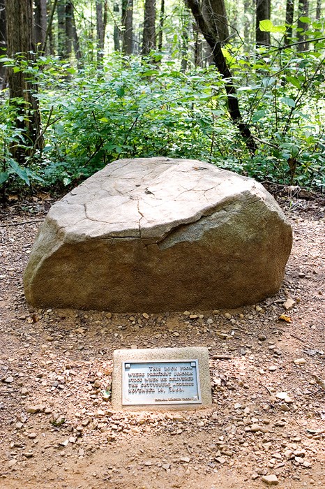 Large boulder on side of trail with plaque in front.