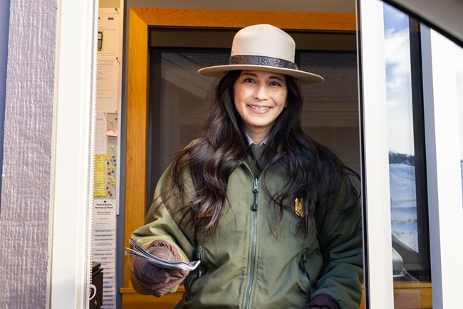 A park ranger hands a map out of a window at an entrance station.