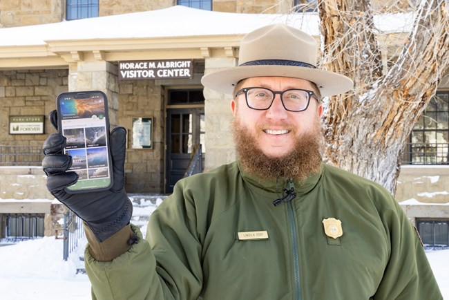 A park ranger shows the NPS App on a phone.