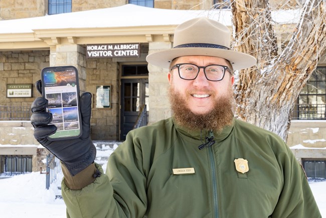 Enhance your Experience A park ranger shows the NPS App on a phone.