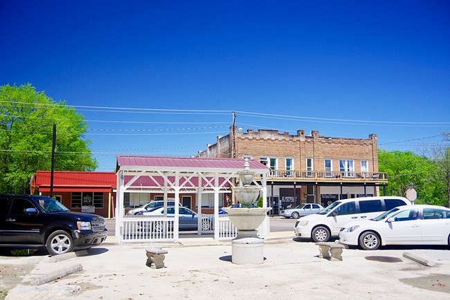 Saltillo Main Street Street scene with vehicles in front of a brown masonry building and a red building