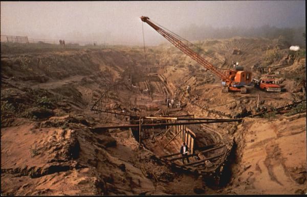 crane near open, muddy hole