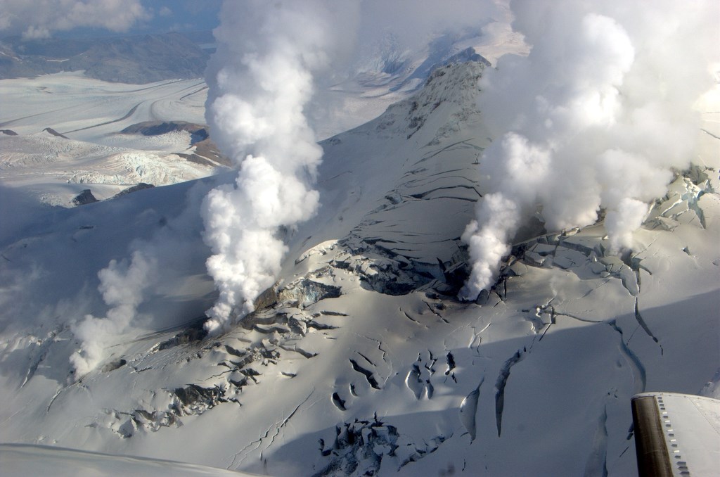 aerial view of a snowy mountainside with steaming fumaroles