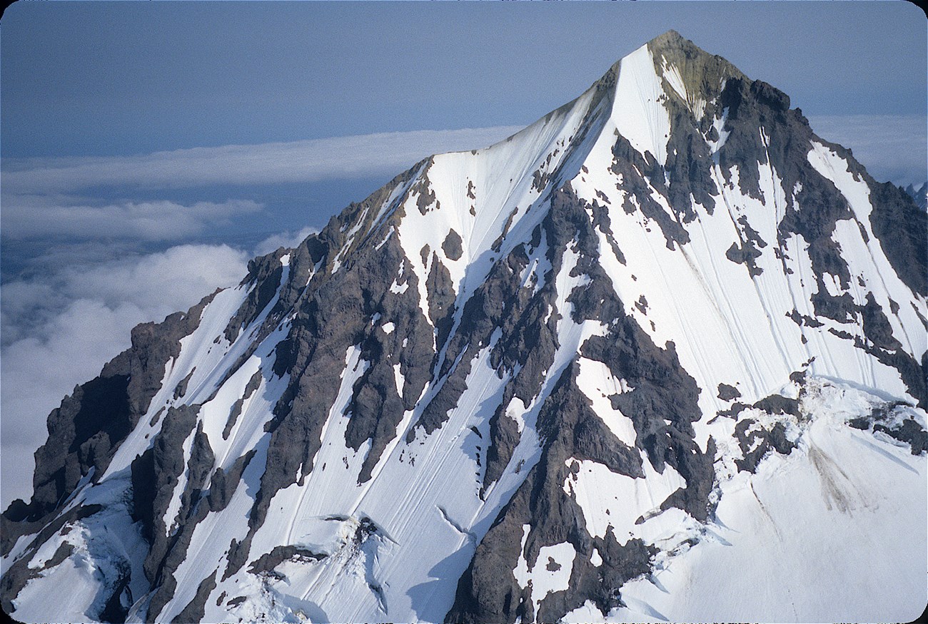 photo of a steep volcanic peak with partial snow cover