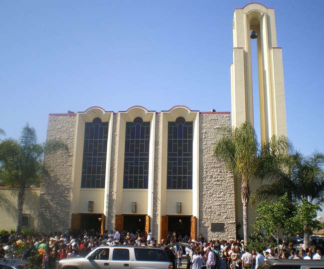 Stone and brick church building with crowds outside