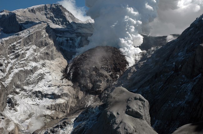 mountain top crater with a dome of rock and plume of steam