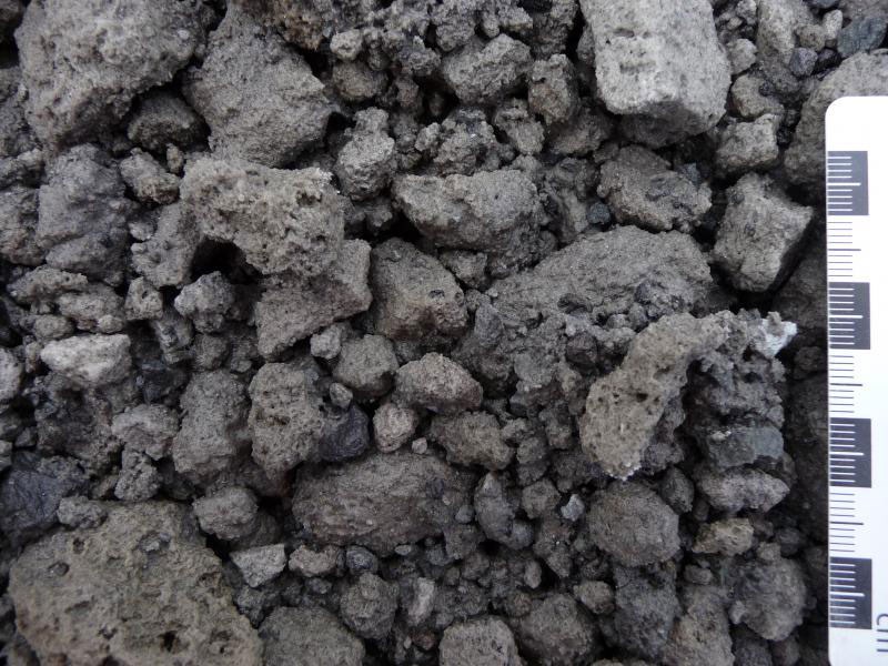 1246564255_ photo of blocky rocks that have small air holes, shown with a ruler for scale.