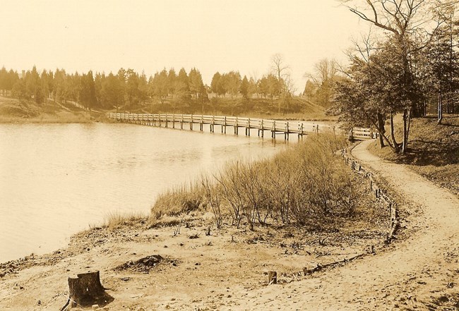 trail near water with boardwalk footbridge crossing it