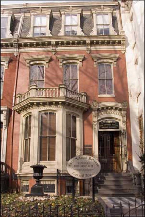 Front of a brick house with a bay window.