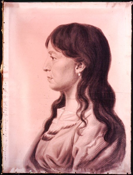 1384 A profile portrait of Yellow Corn; she is facing to the left. Her hair is straight and extends over her shoulders. She is wearing a simple dress and an earring is seen in her left ear.