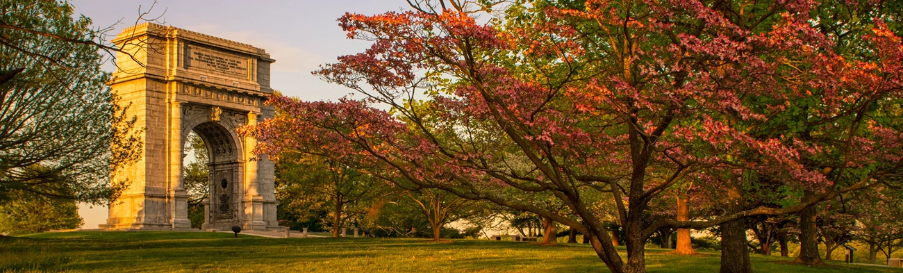 The National Memorial Arch behind pink blooming trees. The National Memorial Arch behind pink blooming trees.