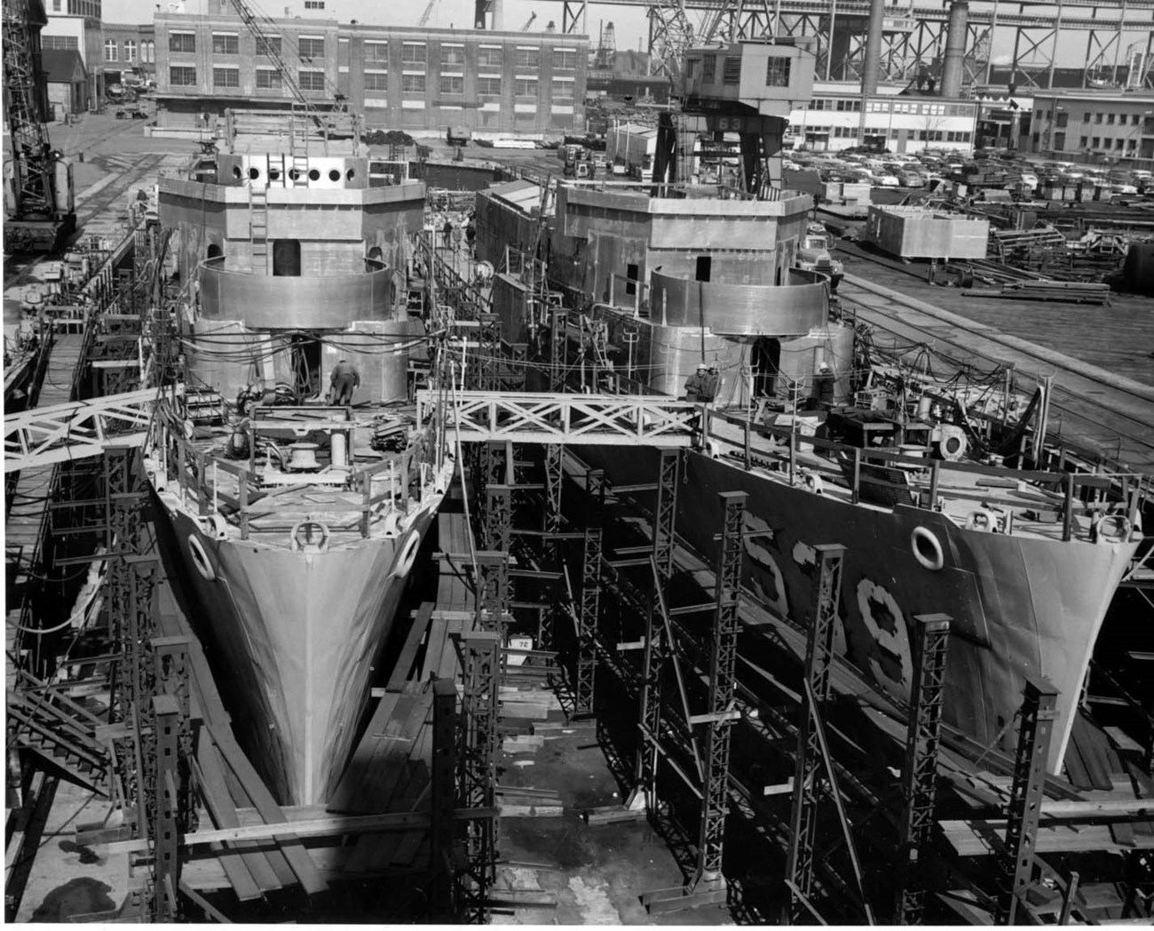 Two destroyer escorts under construction in a dry dock at a navy yard.