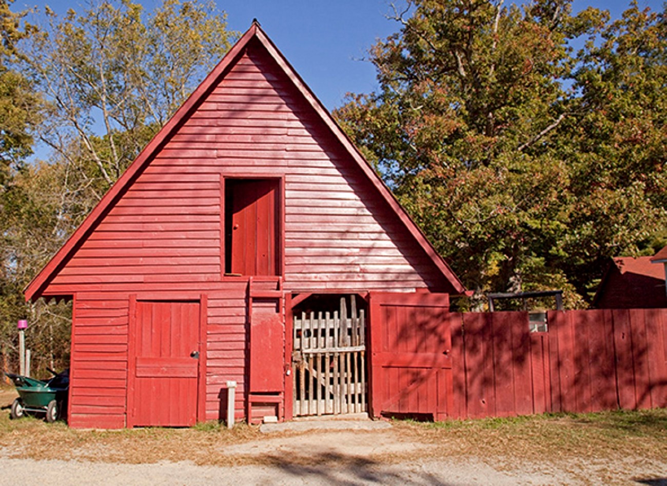 15 buck quarters A small red A frame barn with a wooden fenced play yard