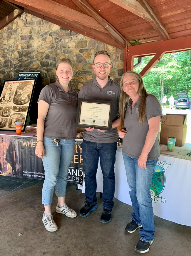 Three people standing with a certificate