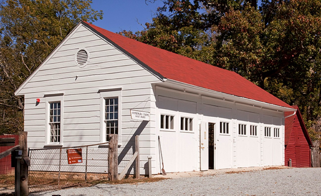 16 barn garage A white garage with a red roof and several doors holds a few vehicles and farm equipment