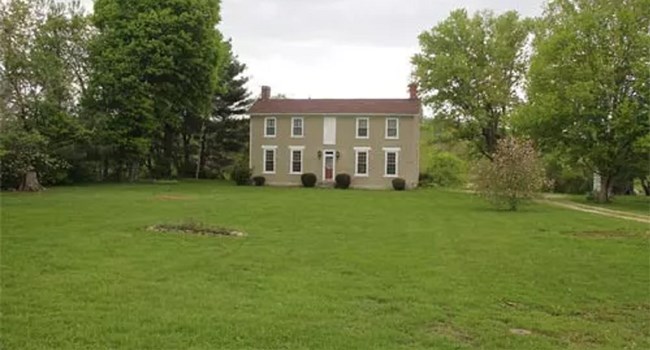 A historic two-story home in a large field