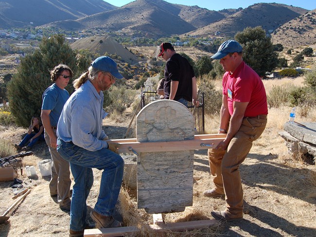 The simple wooden clamp system allows two people to safety lift the marble grave marker.