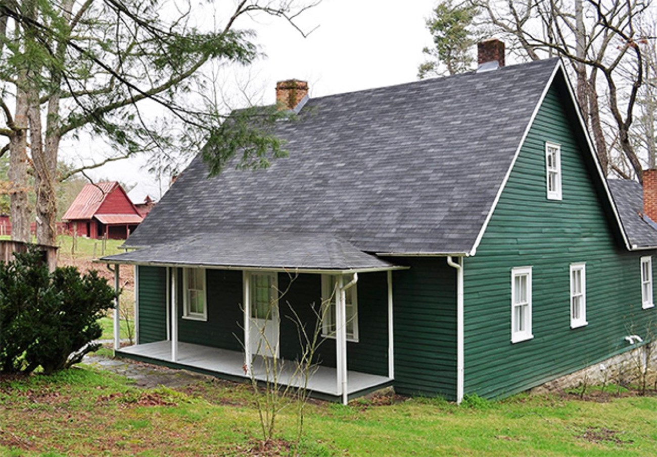 19 farm manager Green farm house with front porch and outbuildings