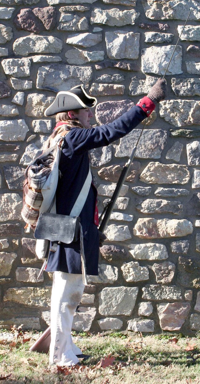 Continental Army soldier drills, using a ramrod to muzzle load a cartridge into a musket. Continental Army soldier drills, using a ramrod to muzzle load a cartridge into a musket.