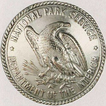 Round silver National Park Service badge with an eagle in the center.