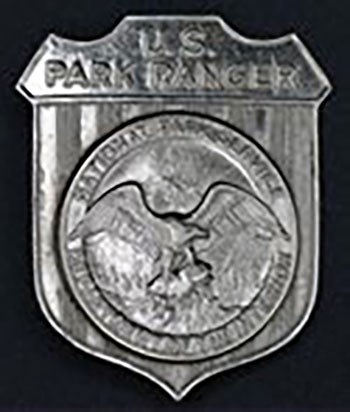 badge 1920 Shield badge with Round silver National Park Service badge with an eagle in the center.