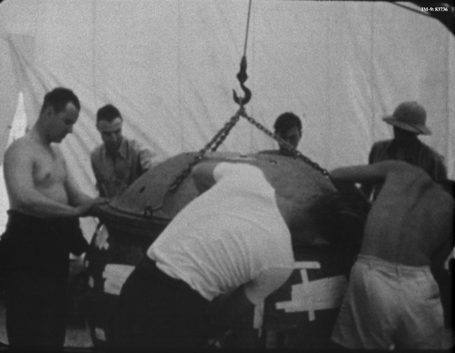 Black and white photo of several scientists assembling a large sphere
