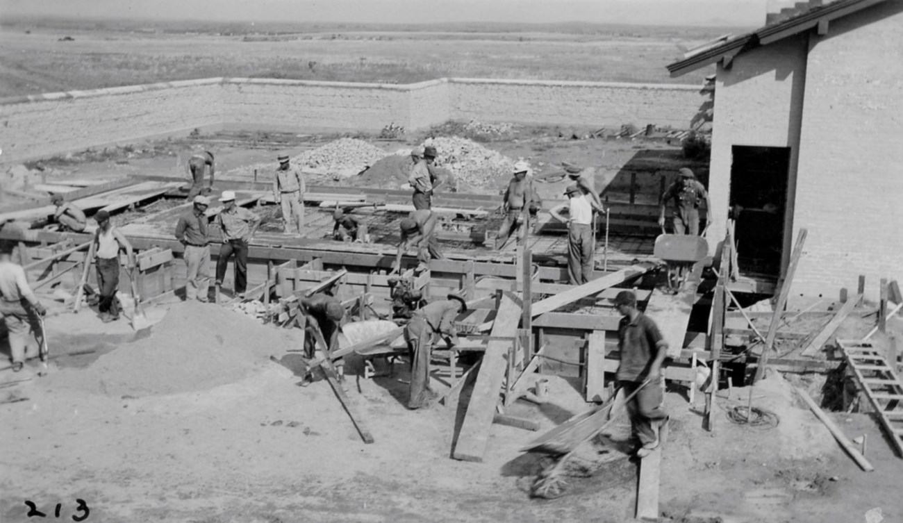 A group of men work on the foundation of a building.